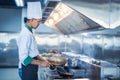 Chef in restaurant kitchen at stove and pan cooking flambe on food Royalty Free Stock Photo