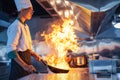 Chef in restaurant kitchen at stove and pan cooking flambe on food Royalty Free Stock Photo