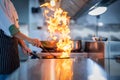 Chef in restaurant kitchen at stove and pan cooking flambe on food Royalty Free Stock Photo
