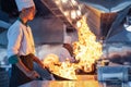 Chef in restaurant kitchen at stove and pan cooking flambe on food Royalty Free Stock Photo