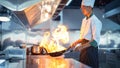 Chef in restaurant kitchen at stove and pan cooking flambe on food Royalty Free Stock Photo