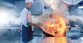 Chef in restaurant kitchen at stove and pan cooking flambe on food Royalty Free Stock Photo