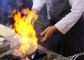 Chef in restaurant kitchen at stove with pan, doing flambe on food Royalty Free Stock Photo