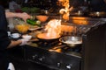 Chef in restaurant kitchen at stove with pan, doing flambe on food. low ligth selective focus. Royalty Free Stock Photo