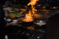 Chef in restaurant kitchen at stove with pan, doing flambe on food. low ligth selective focus. Royalty Free Stock Photo