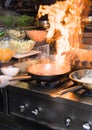 Chef in restaurant kitchen at stove with pan, doing flambe on food. low ligth selective focus. Royalty Free Stock Photo