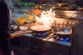 Chef in restaurant kitchen at stove with pan, doing flambe on food. low ligth selective focus. Royalty Free Stock Photo