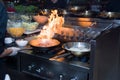 Chef in restaurant kitchen at stove with pan, doing flambe on food. low ligth selective focus. Royalty Free Stock Photo