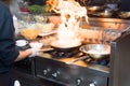 Chef in restaurant kitchen at stove with pan, doing flambe on food. low ligth selective focus. Royalty Free Stock Photo