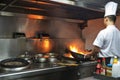 Chef in restaurant kitchen at stove with pan