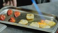 The chef roasts the ingredients to decorate the dish. Strawberries are baked with fire, close-up. Restaurant kitchen