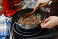 The chef roasts the mince in a deep pan. Ready stuffing with onions in a bowl on the background of spices and greens