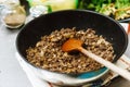 The chef roasts the mince in a deep pan. Ready stuffing with onions in a bowl on the background of spices and greens