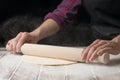 Chef roll out the dough on the working surface. Black background Royalty Free Stock Photo