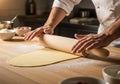 A chef rolls out dough on a wooden countertop using a rolling pin. The scene is set in a kitchen, Royalty Free Stock Photo