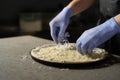 Chef's gloved hands place grated cheese on a round vegetarian pizza. Ingredients in a pizzeria. Italian food concept Royalty Free Stock Photo