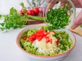 Chef`s hand adds freshly chopped cilantro to avocado dip. Making guacamole with ingredients