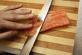 Chef`s hand cutting fish into thin slices with a knife Royalty Free Stock Photo