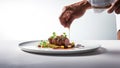 Chef\'s hand garnishing a beef steak with vegetables on a white plate