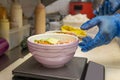 Chef's hands gloved in blue plastic preparing a poke bowl of salmon with masago roe and avocado and thinking about it on a