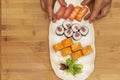 Chef's hands preparing a white tray of sushi and maki of red tuna and uramaki