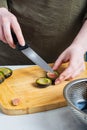 the chef`s hands remove the plum stone on the cutting Board with a knife