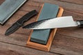 Chef`s and pocket knives and whestones on a rustic wooden table Royalty Free Stock Photo