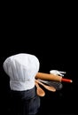 A chef's toque with kitchen utensils on black Royalty Free Stock Photo