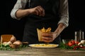 Chef salting in the envelope french fries ready, on the background with vegetables. Cooking tasty but harmful food. Background for Royalty Free Stock Photo