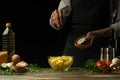 Chef salting french fries on a background with vegetables. Cooking tasty but harmful food Royalty Free Stock Photo