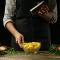 Chef salting french fries on a background with vegetables. Cooking tasty but harmful food Royalty Free Stock Photo