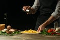 Chef salting french fries ready, on the background with vegetables. Cooking tasty but harmful food. Background for design and menu Royalty Free Stock Photo