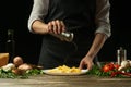 Chef salting french fries ready, on the background with vegetables. Cooking tasty but harmful food. Background for design and menu Royalty Free Stock Photo