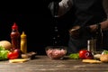 Chef salting minced meat to create a burger patty. Against the background with ingredients for a burger. Gastronomy, recipes, Royalty Free Stock Photo