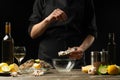 Chef salting oyster with lemon on the background of dry wine on a dark background, horizontal photo, menu, restaurant, Italian