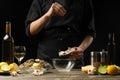 Chef salting oyster with lemon on the background of dry wine on a dark background, horizontal photo, menu, restaurant, Italian