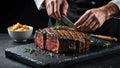 Chef is salting or seasoning raw ribeye steak laying on graphite serving board
