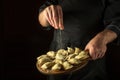 The chef salts raw dumplings on a cutting kitchen board before cooking. Black space for menu or recipe Royalty Free Stock Photo