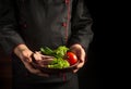 The chef serves a plate of sliced steak and vegetables. The concept of cooking on a dark background Royalty Free Stock Photo