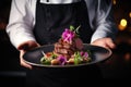 Chef serving a dish with artistic presentation, adorned with flowers and sauce Royalty Free Stock Photo