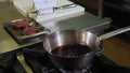 Chef sets fire to red wine in a saucepan to evaporate alcohol, preparing sauce.