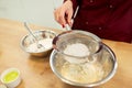 Chef sifting flour in bowl making batter or dough