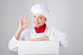 Chef Sign. Woman cook / baker looking over paper sign billboard. Surprised and funny expression woman on white background Royalty Free Stock Photo