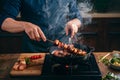 Chef skillfully grills flavorful barbecue skewers on a smoky stove top