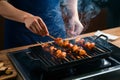 Chef skillfully grills flavorful barbecue skewers on a smoky stove top