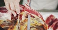 A chef slices jamon leg or dry-cured ham. Close-up shot Royalty Free Stock Photo