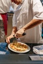 Chef slices a Puccia Al Tarfuto by knife: Thin crispy dough filled with mascarpone, stracciatella, parmesan and black truffle