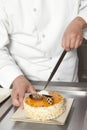 Chef Slicing Cake At Counter In Commercial Kitchen