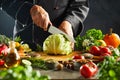 Chef slicing through a fresh green head of cabbage