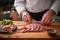 chef slicing fresh tuna for sashimi on a wooden board